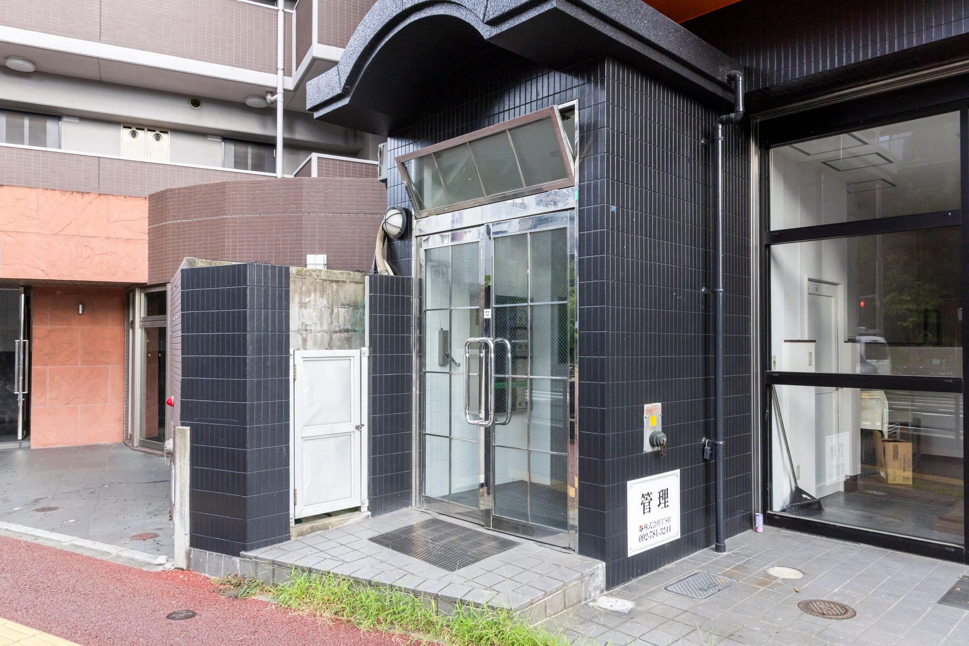 建物のエントランス。黒いタイルの外壁とガラスの扉